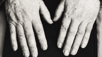 A black and white photo of Seamus Heaney's hands on top of a book