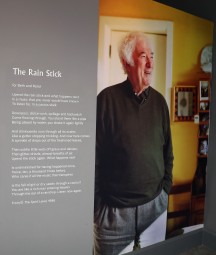 Photograph of Seamus Heaney beside a rainstick which visitors can turn in the exhibition