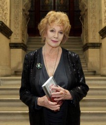 Edna O'Brien holding book standing on stairs at the NLI