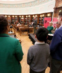 The backs of three children participating in Poetry Aloud 2023