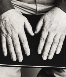 A black and white photo of Seamus Heaney's hands facing palms up on top of a book