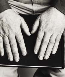 A black and white photo of Seamus Heaney's hands on top of a book