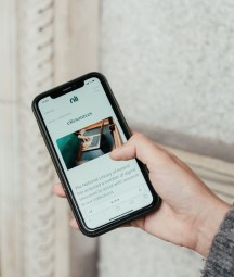 A woman's hand holding a phone open on the NLI's website