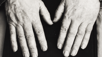 A black and white photo of Seamus Heaney's hands facing palms up on top of a book