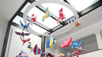 image of brightly coloured floating sculpture with origami style birds flying in an upwards spiral