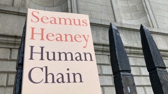 a copy of seamus heaney's poetry collection 'human chain' along a wrought iron fence with empty alcoves behind