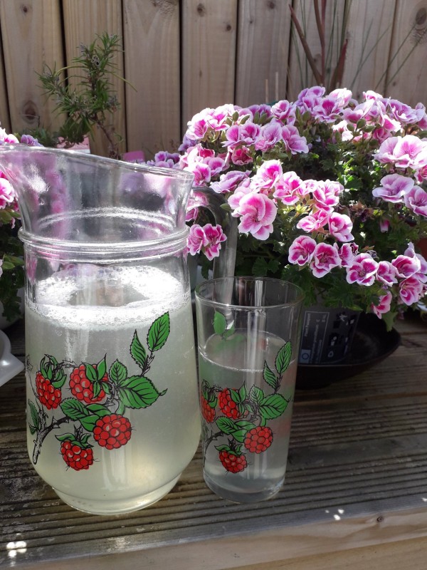 Lemonade in a jug next to flowers