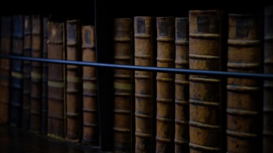 Old books lined up on a shelf. 