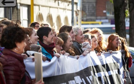 A number of women holding up a large banner