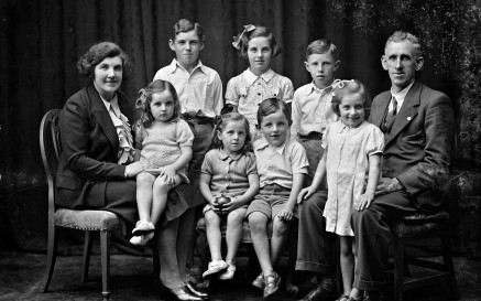 Black and White studio portrait of the Phelan family, featuring both parents and 7 children, ranging in age from about 3 to 10 years of age.  