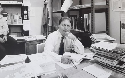 Black and white photograph of a man sitting at a desk