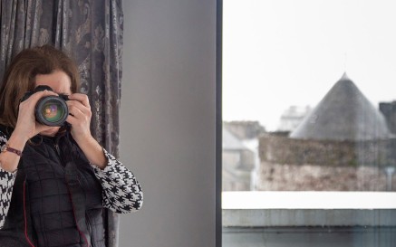 An image of the photographer Paula Nolan, from behind her camera. Waterford city can be seen from the window