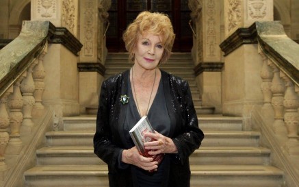 Edna O'Brien holding book standing on stairs at the NLI