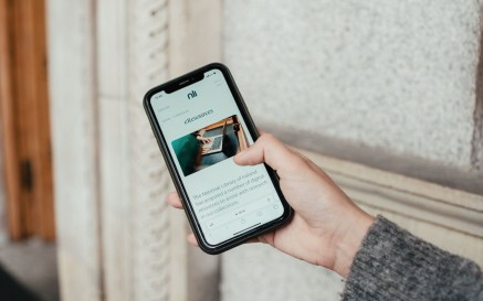 A woman's hand holding a phone open on the NLI's website